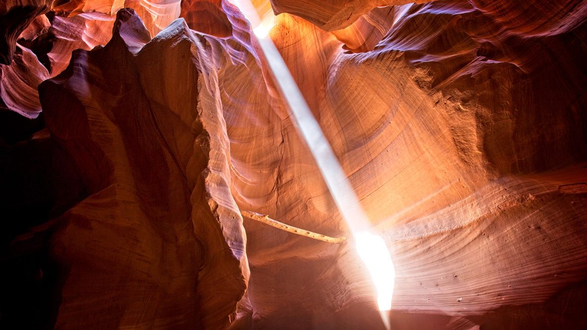 A beam of sunlight reaching the floor of a sandstone slot canyon