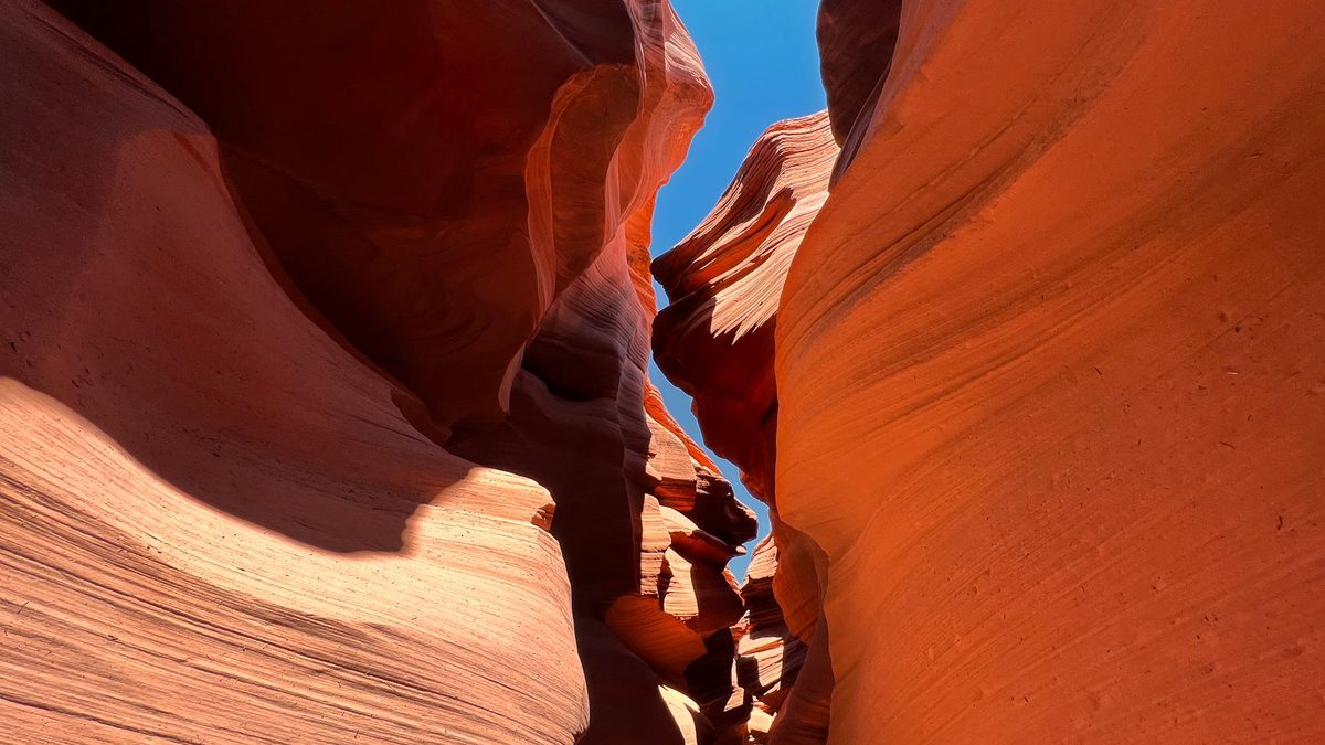 A narrow slot of red sandstone with blue sky above