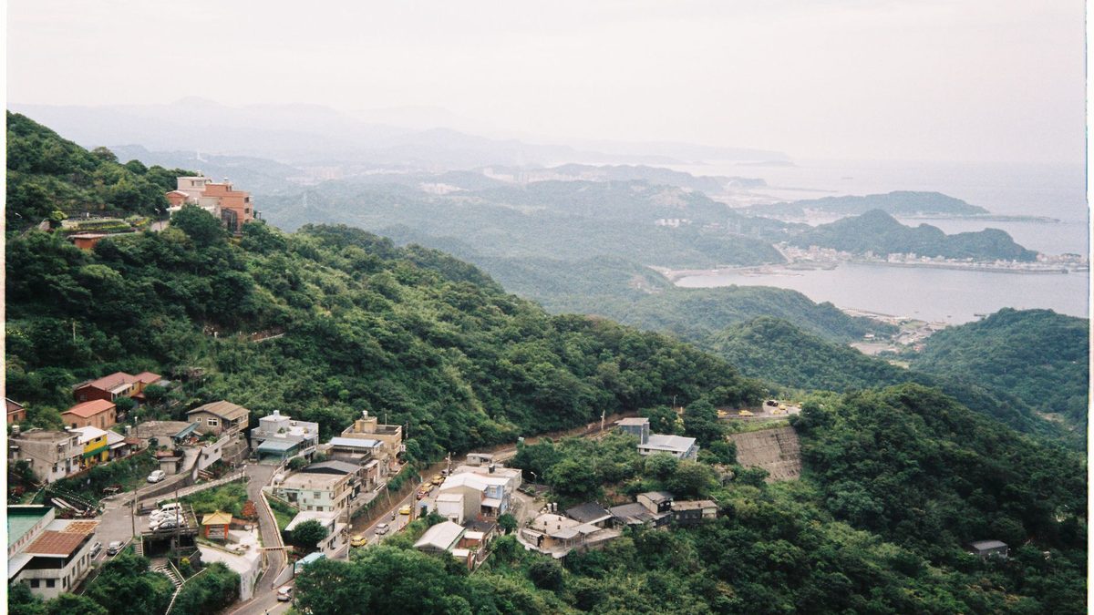 Green hills and sea around a hillside village in misty light