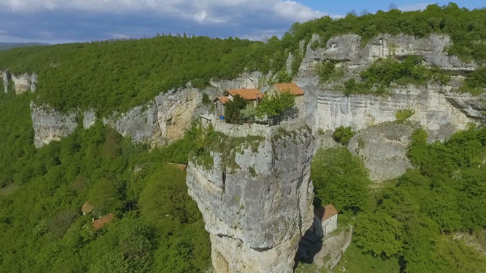 The Katskhi Pillar, a tall limestone tower with a small church on top, above green forest
