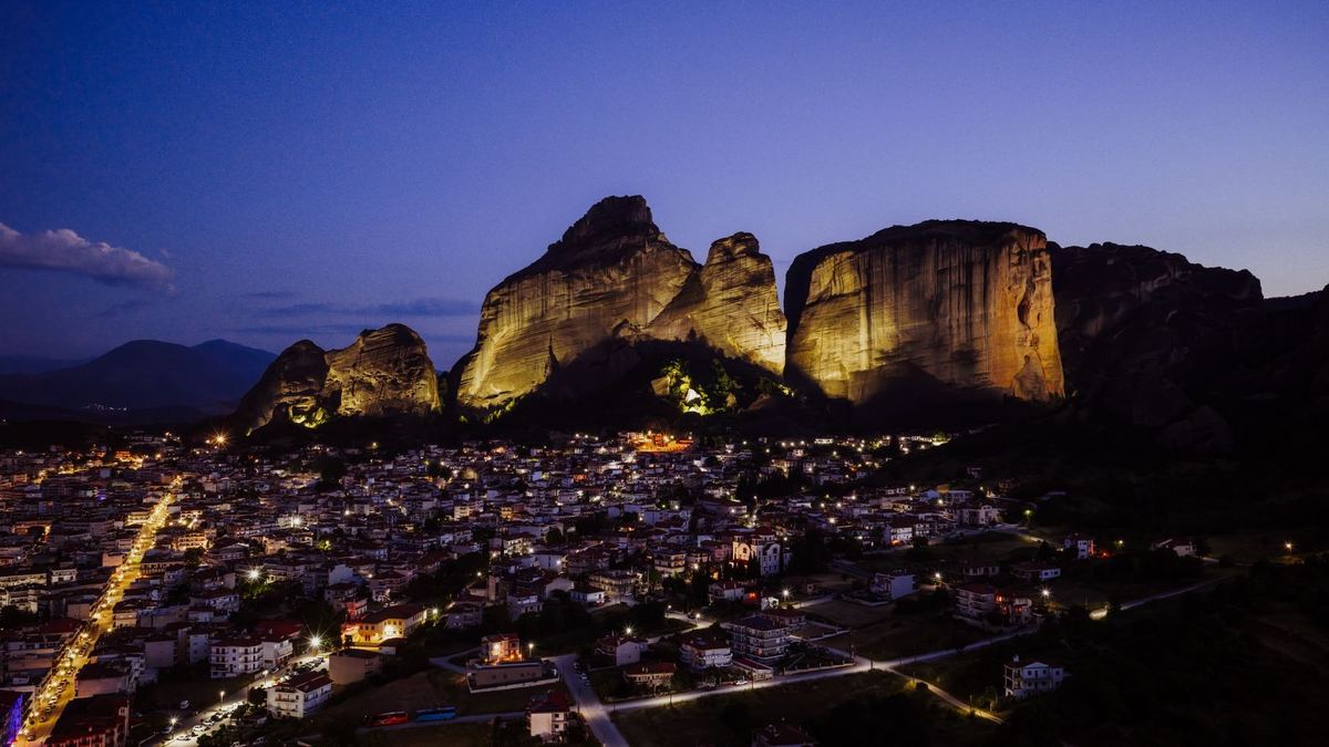 Kalambaka town lit up at dusk below the floodlit Meteora rocks