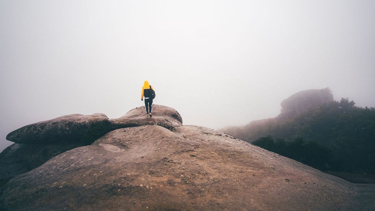 A lone hiker standing on a rock in the fog at Meteora