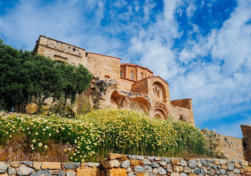 A Byzantine church above a wall covered in wild flowers