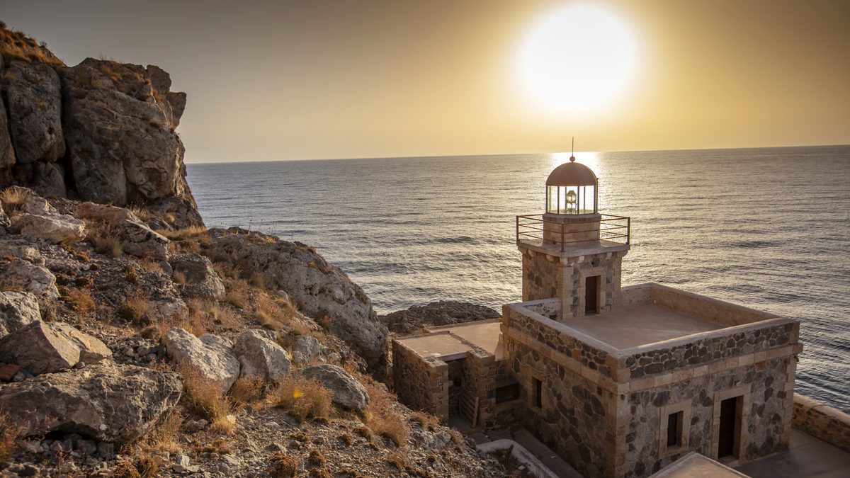 A lighthouse silhouetted against the setting sun