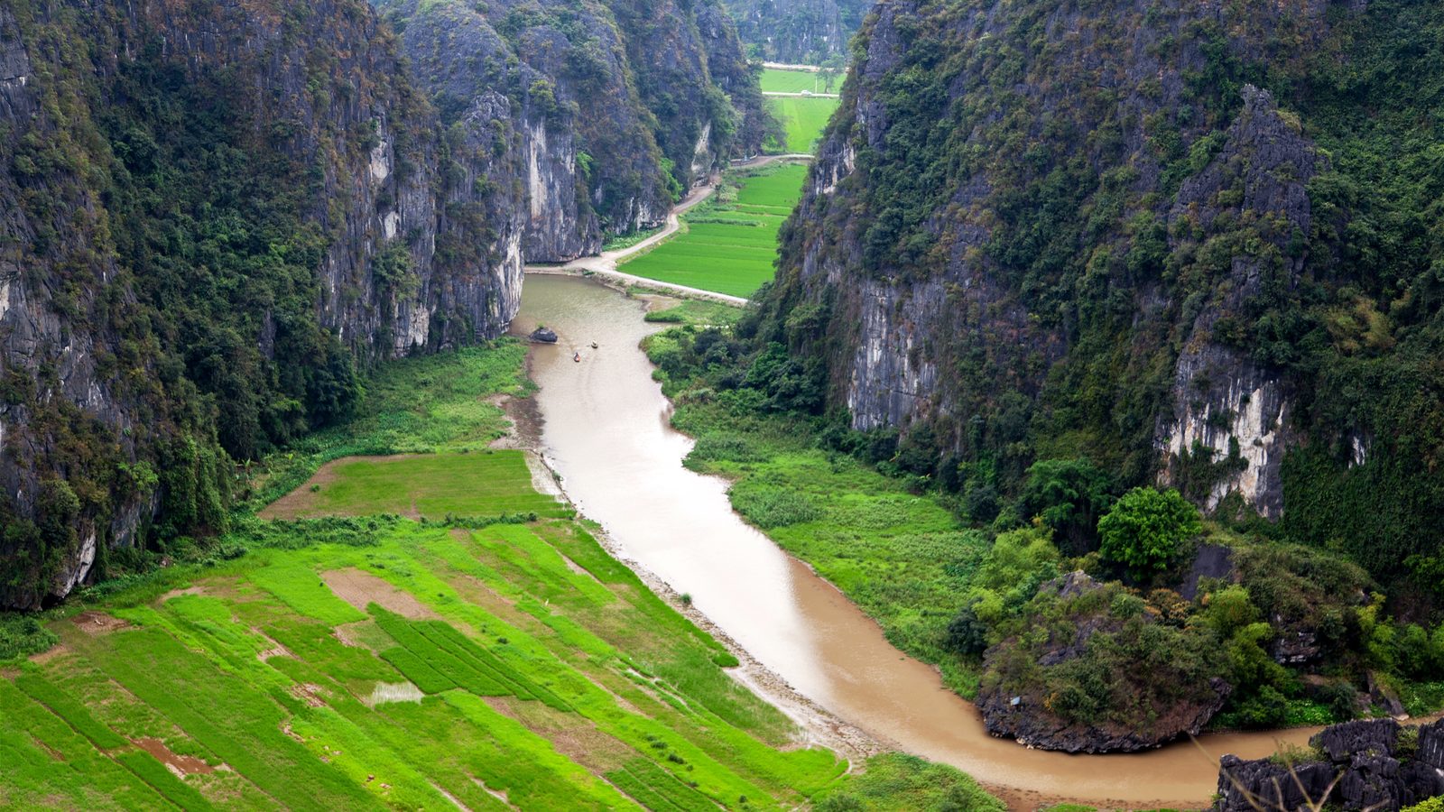 A river winding between limestone cliffs and green rice fields at Ninh Binh