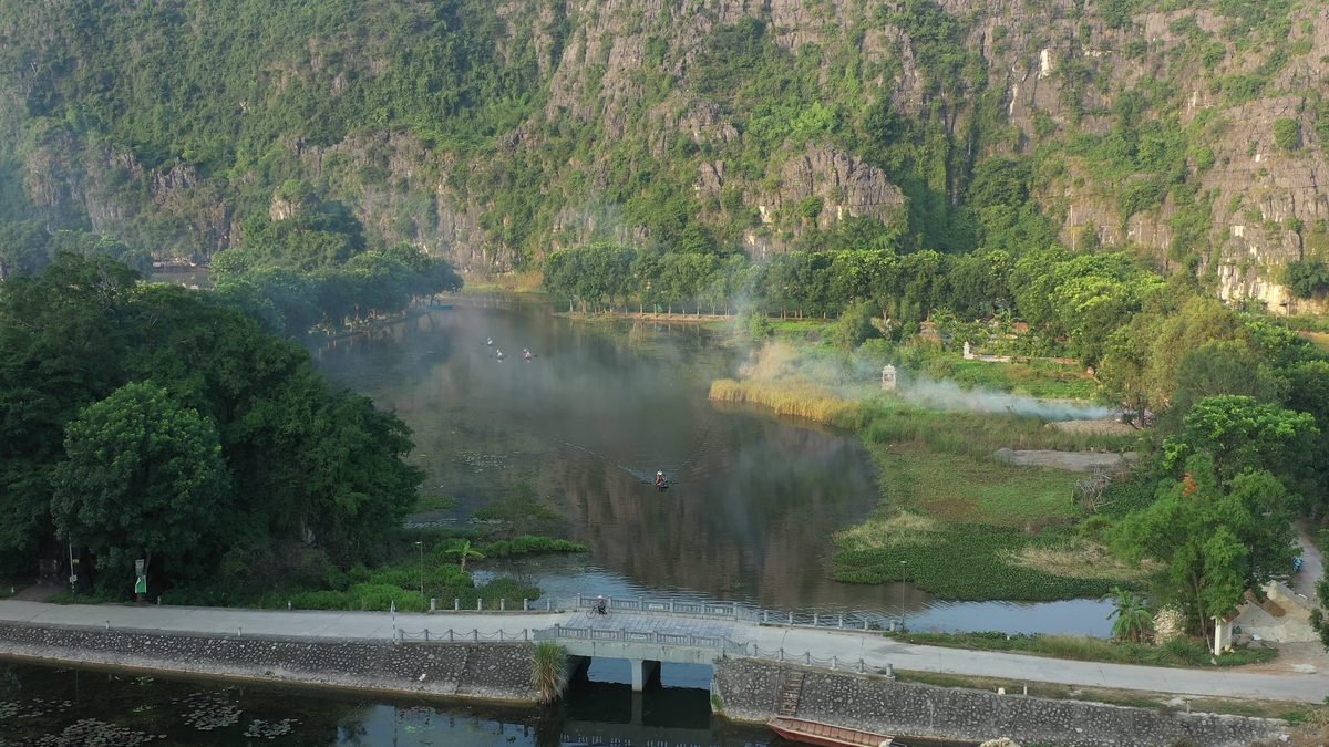 A river and a dock beside a limestone cliff in morning mist