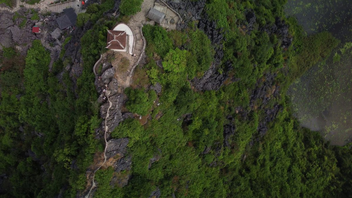 A stone staircase winding up a limestone ridge to a temple