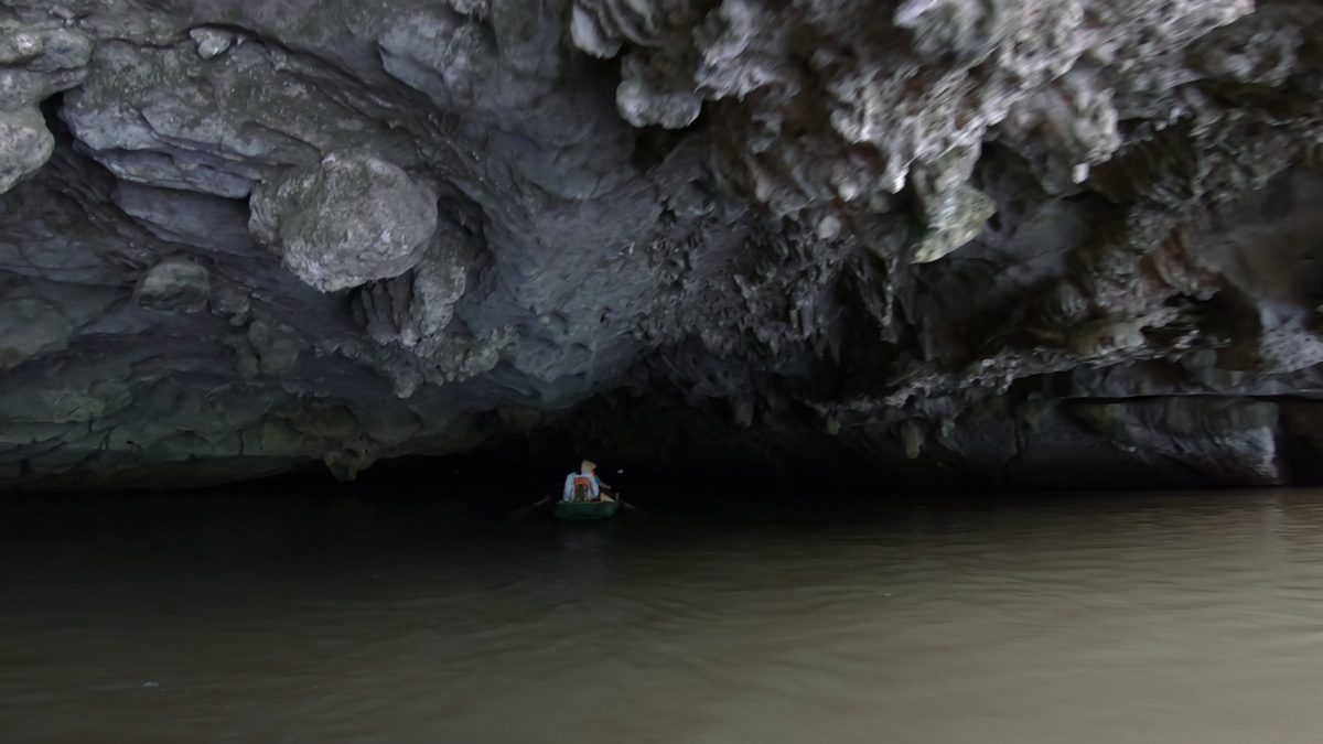 A tour boat on a river below green hills