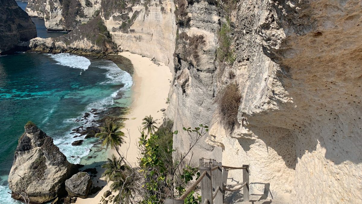 A stone stairway down to a white-sand beach