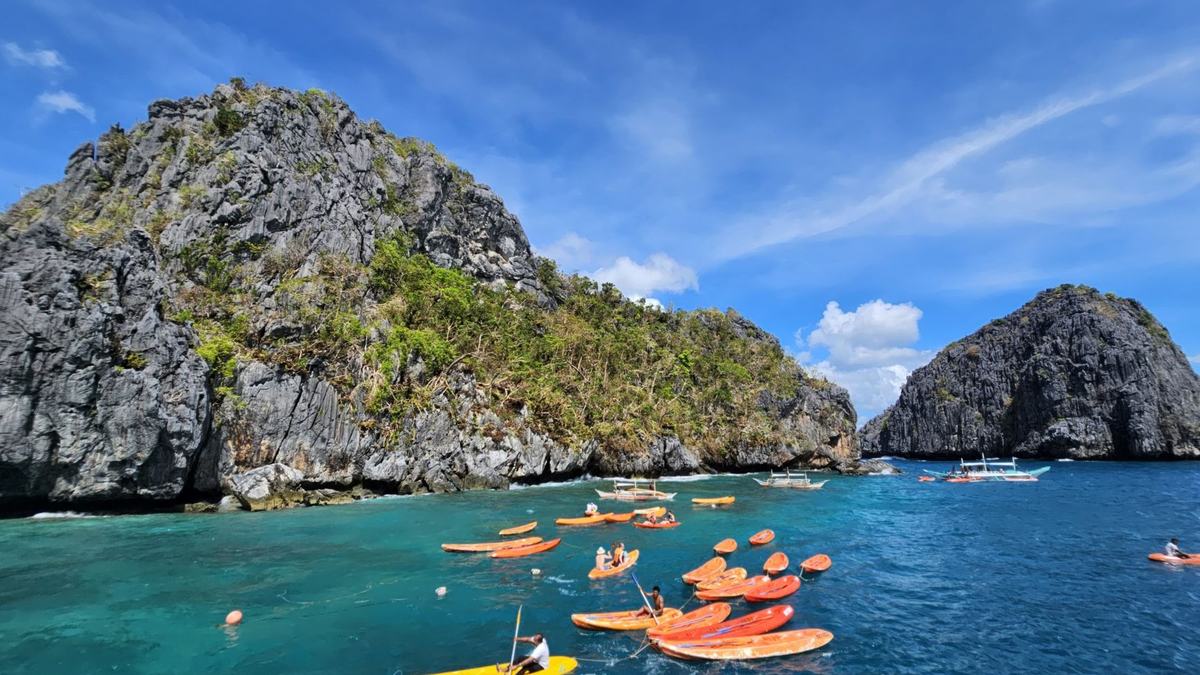 Kayakers paddling between limestone cliffs in El Nido
