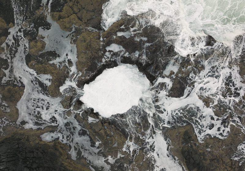 Spray and foam around the well on a black rock shelf