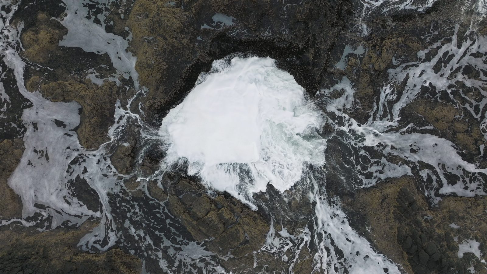 Seawater swirling into the rock hole of Thor's Well from above