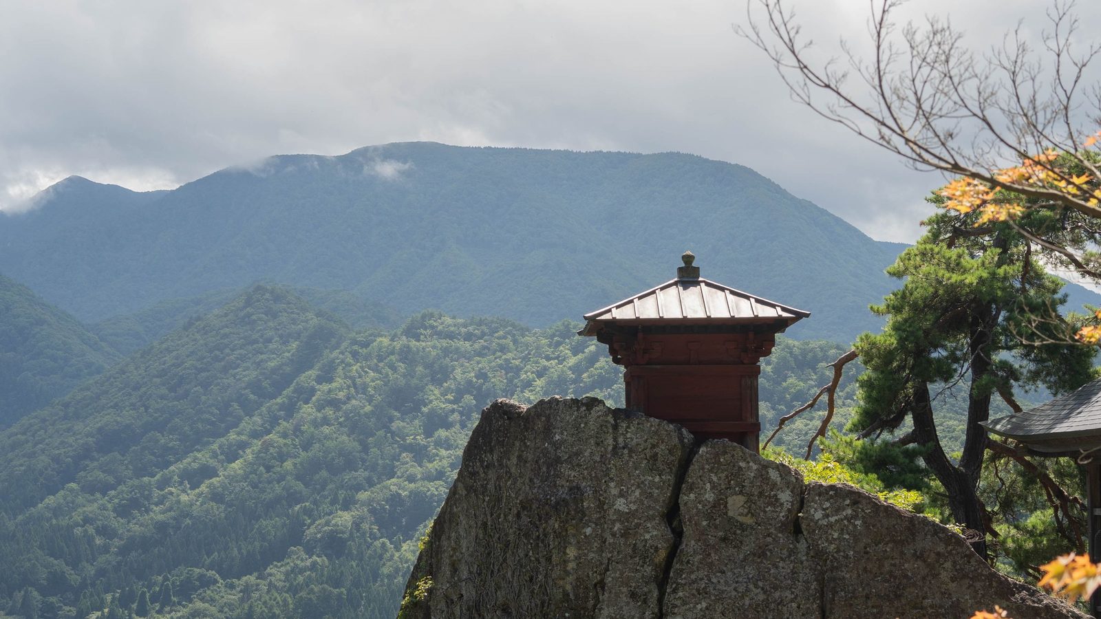 Yamadera temple buildings perched on a cliff above the forest